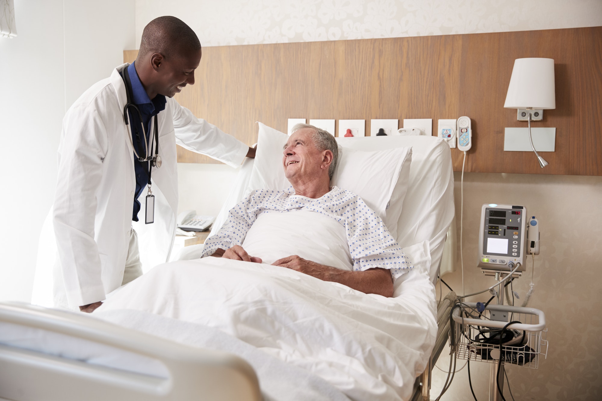 Doctor Visiting And Talking With Senior Male Patient In Hospital Bed