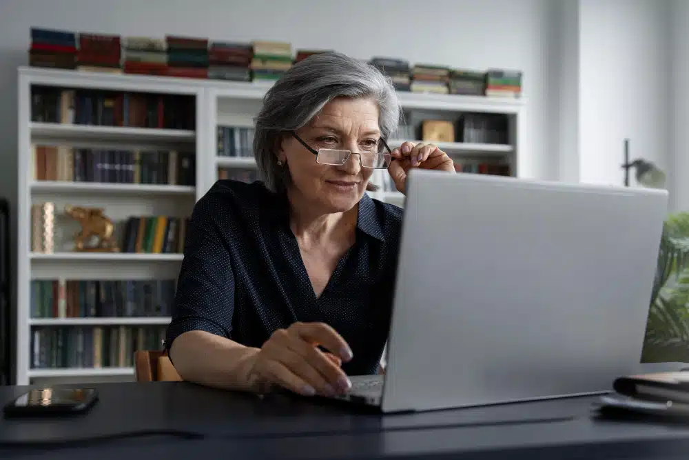 Older woman looking at laptop in her office.