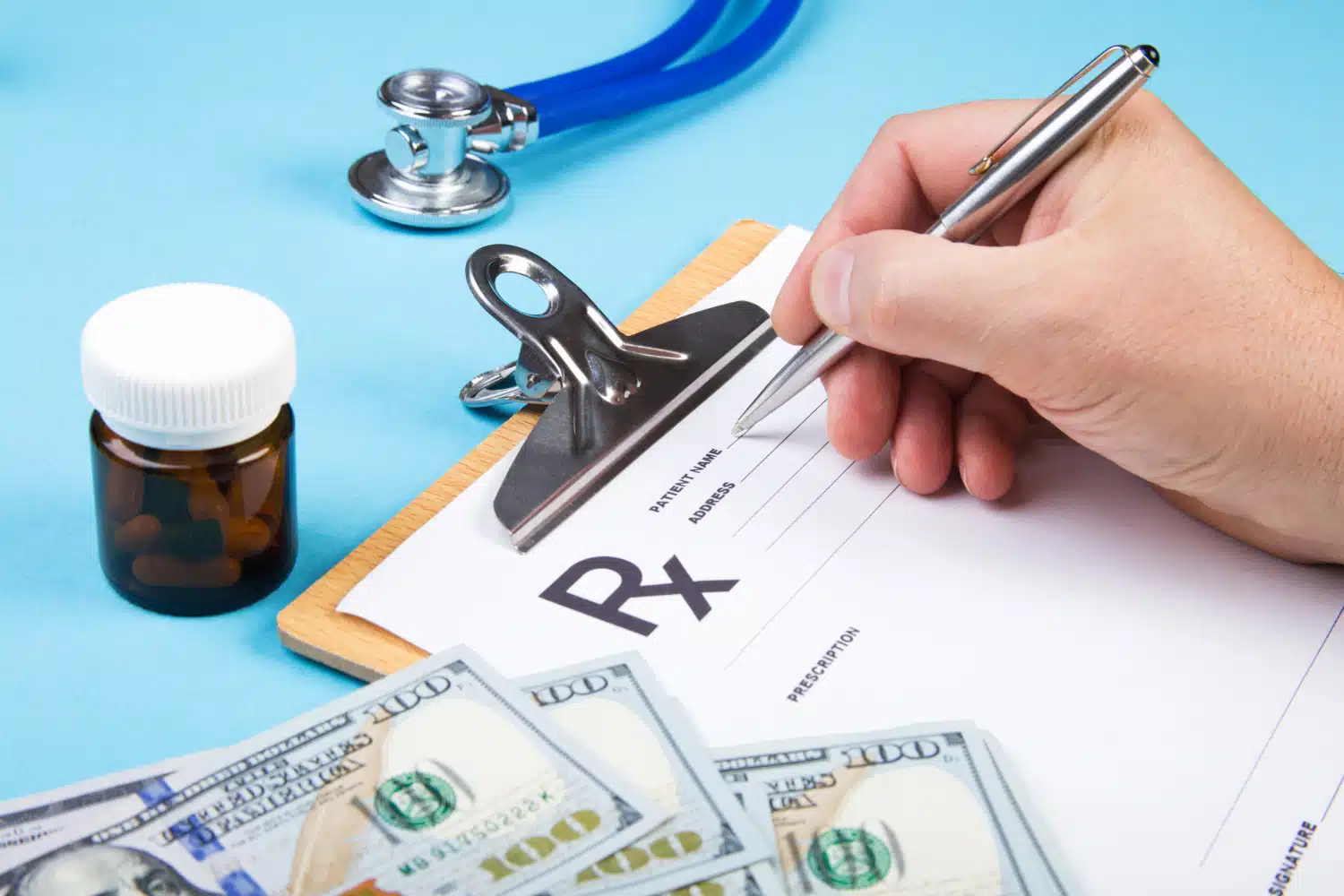 Male doctor or pharmacist holding jar or bottle of pills in hand on a background of dollars banknotes and writing prescription on a special form.