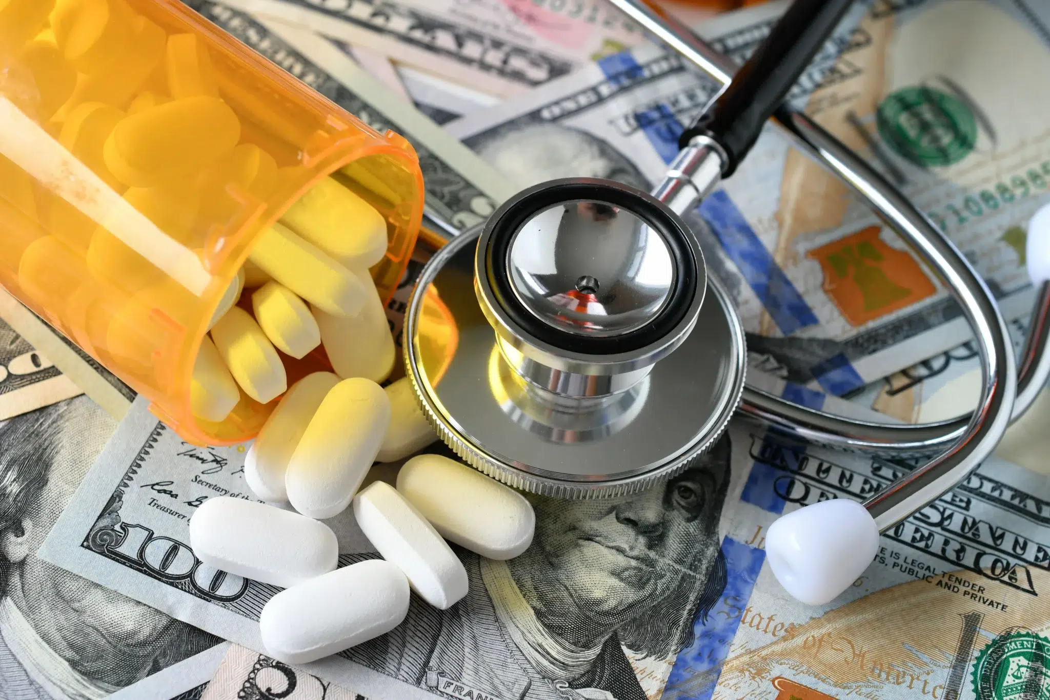 Medicare prescription drug costs concept — pills, stethoscope, and money.